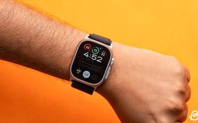 hand wearing Apple Watch Ultra in front of an orange background