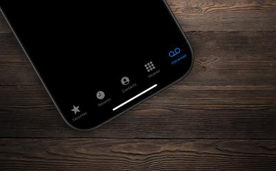 Image of an iPhone kept on a table with the Phone app open with the Voicemail option highlighted