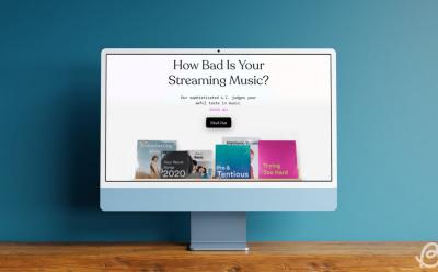 shot of an iMac placed on wooden desk showcasing the How Bad is Your Spotify tool on the screen
