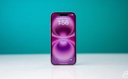 iPhone 16 placed upright on a white flat surface with a pink gradient wallpaper