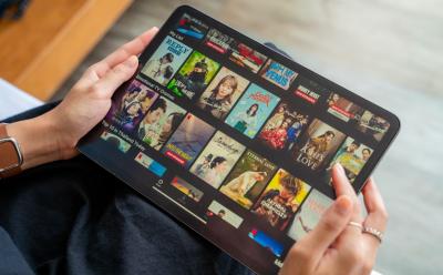 Person holding a tablet with the Netflix app browsing through different titles