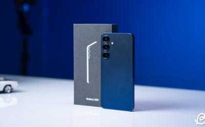 angled shot of the Galaxy S25 Plus rear panel with the phone standing upright with its box on a flat desk