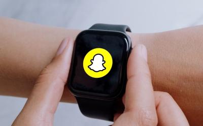 person interacting with Apple Watch on their wrist with Snappchat logo for illustration