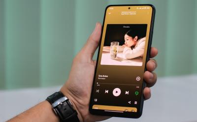 Shot of hand hodling a phone using Spotify Premium and playing a song